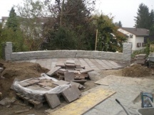 Sitzplatz im Garten mit Granitmauer und Porphyrsteinplatten auf Betonplatte. EFH in Mhlin.